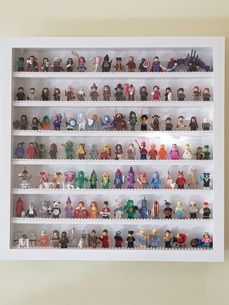  Close-up of LEGO minifigures displayed behind the glass front of a display frame.