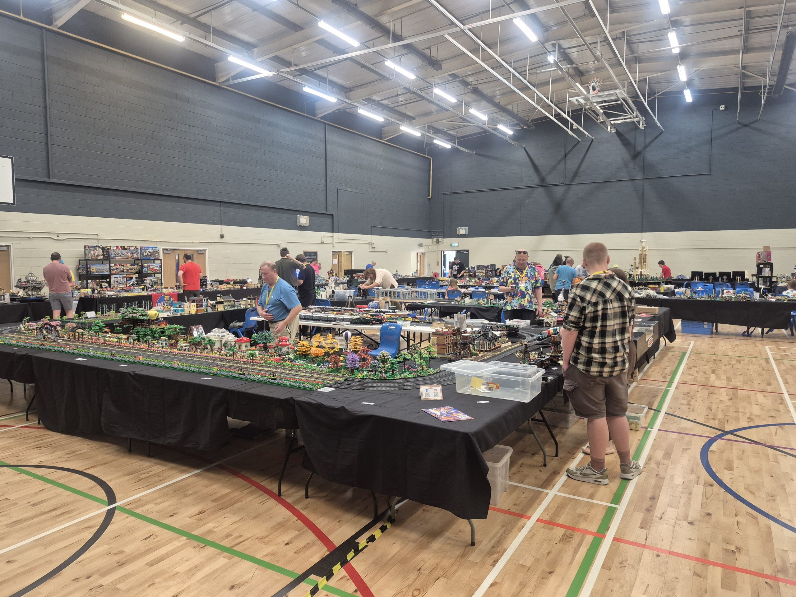 A detailed LEGO train layout with scenery, trees and buildings on display